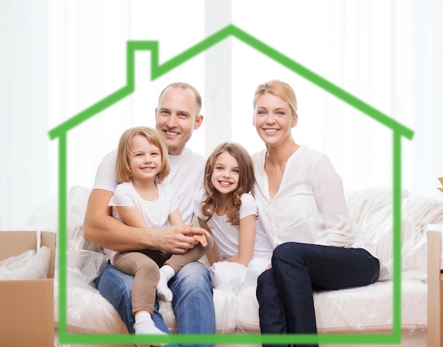 familie, kinderen, huisvesting en huisconcept - glimlachende ouders en twee kleine meisjes thuis achter groen huissymbool