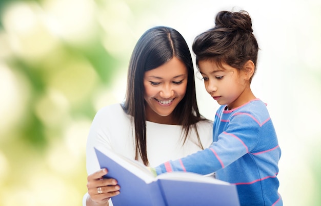 familie, kinderen, onderwijs, school en gelukkige mensen concept - gelukkige moeder en dochter leesboek over groene achtergrond