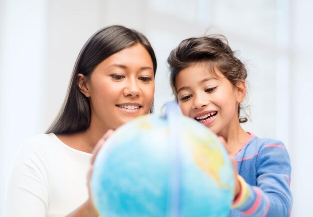 familie, kinderen, onderwijs, school en gelukkige mensen concept - moeder en dochter met globe