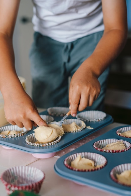 Familie koken muffins samen in huis keuken jongen rauw deeg gieten in siliconen mallen Moederdag familie zelfgemaakte gezonde voeding bakken