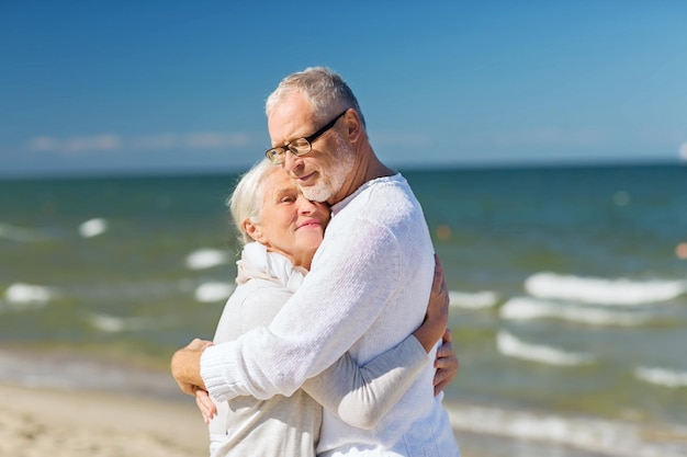 familie, leeftijd, reizen, toerisme en mensen concept - gelukkig senior paar knuffelen op zomerstrand