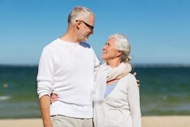 familie, leeftijd, reizen, toerisme en mensen concept - gelukkig senior paar knuffelen op zomerstrand