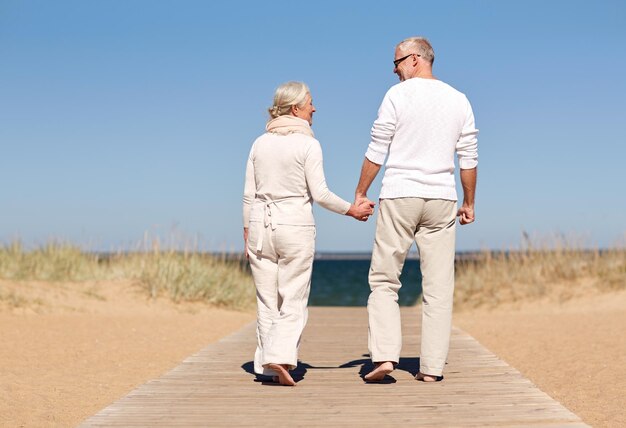 familie, leeftijd, reizen, toerisme en mensen concept - gelukkige senior paar hand in hand en wandelen op zomer strand