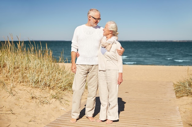 familie, leeftijd, reizen, toerisme en mensenconcept - gelukkig hoger paar dat op de zomerstrand spreekt