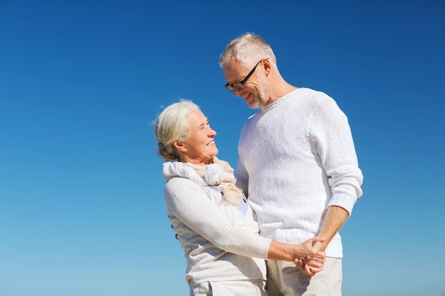 familie, leeftijd, reizen, toerisme en mensenconcept - gelukkig senior paar hand in hand op zomerstrand