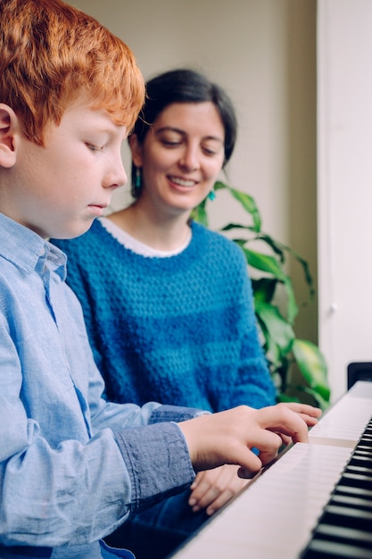 Familie levensstijl tijd samen doorbrengen binnenshuis. kinderen met muzikale deugd en artistieke nieuwsgierigheid. educatieve muzikale activiteiten. de vrouw die van de pianoleraar een kleine lessen van de jongens thuis piano onderwijzen.