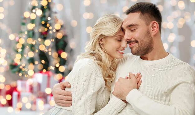 familie, liefde, winter, vakantie en mensenconcept - gelukkig paar over kerstboom steekt achtergrond aan