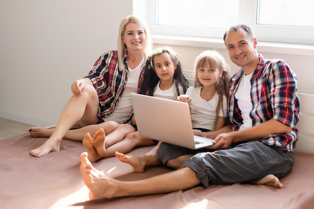 Familie liggend in bed met behulp van een laptop