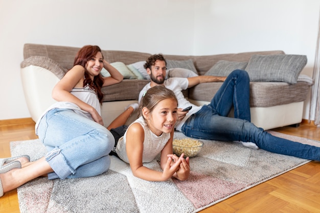 Foto familie liggend op de vloer tijdens het kijken naar tv