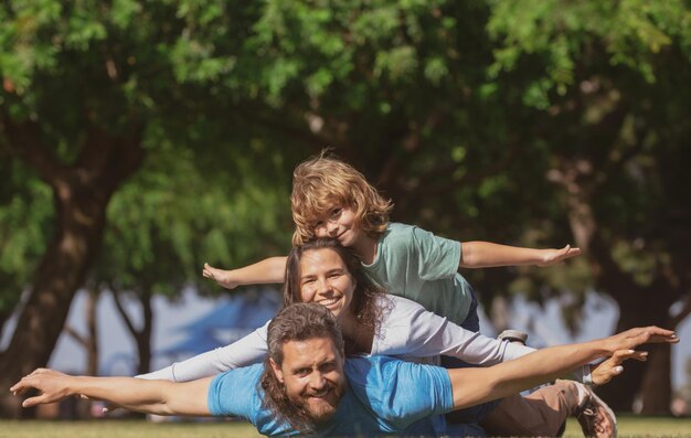 Familie liggend op gras in parkouders die kind meeliften op het plattelandsvliegconcept kleine jongen