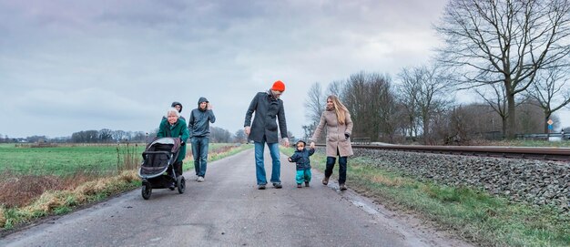 Foto familie loopt in de winter op een onverharde weg tegen de lucht