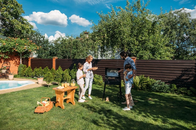 familie met barbecue samen op achtertuin op zomerdag