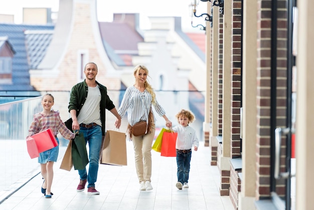 Familie met boodschappentassen hand in hand tijdens het wandelen op het balkon van het winkelcentrum