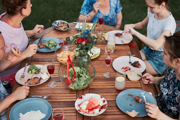Familie met een maaltijd van de grill tijdens een zomer picknick buiten diner in een huis tuin