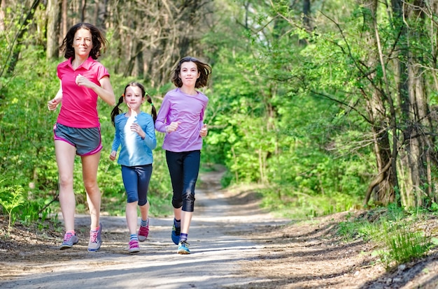Familie met gelukkige actieve moeder en kinderen die buiten joggen, rennen met kinderen in het bos
