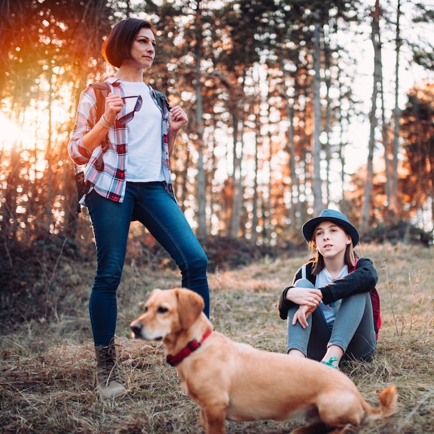 Familie met hond die in bos tijdens zonsondergang rust