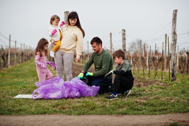 Familie met vuilniszak die afval verzamelt tijdens het schoonmaken in de wijngaarden Milieubehoud en ecologische recycling