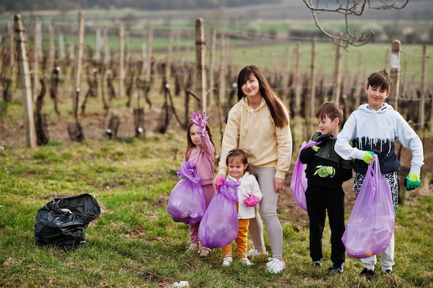 Familie met vuilniszak die afval verzamelt tijdens het schoonmaken in de wijngaarden milieubehoud en ecologische recycling