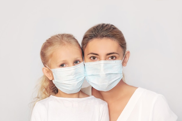Familie moeder en dochter in medische maskers samen op een geïsoleerde achtergrond