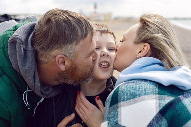 Familie moeder en vader kussen tienerzoon op de wang