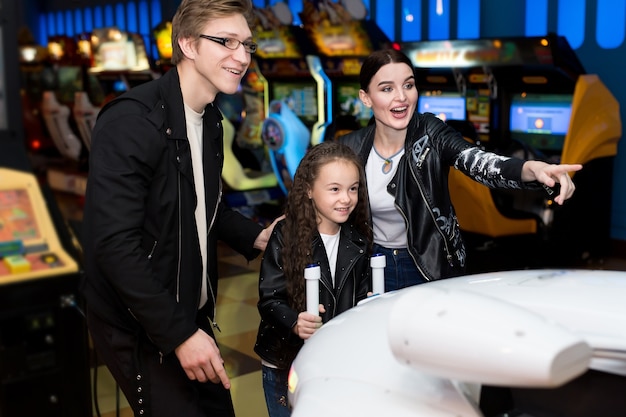 Familie moeder vader dochter arcade games spelen op de computermachines in een pretpark