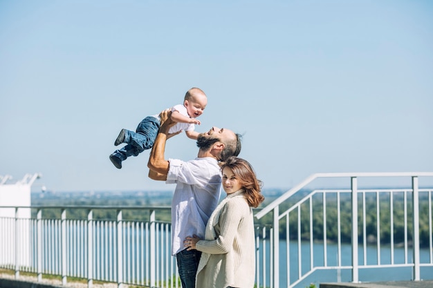 Familie moeder vader en baby blij met een glimlach samen in het Park wandelen langs de promenade in zomer portret