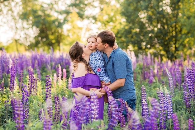 Familie moeder vader en dochtertje in de natuur in een veld met lupines Ouderlijke zorg