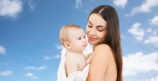 familie, moederschap, ouderschap, mensen en kinderopvang concept - gelukkige moeder met schattige baby over blauwe hemelachtergrond