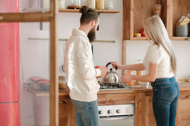 Familie ochtendroutine. Paar dat thee maakt in moderne keuken met houten meubilair.