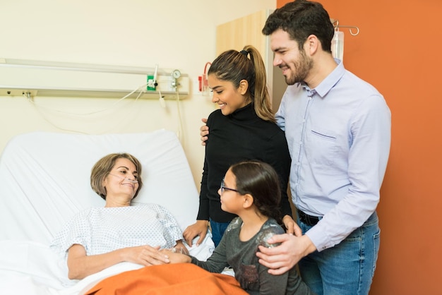 Foto familie op bezoek bij senior patiënt in ziekenhuis tijdens behandeling