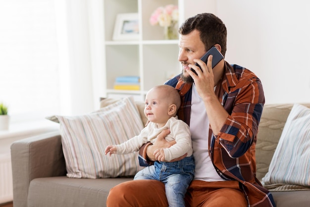 familie ouderschap en mensen concept gelukkige vader met kleine baby jongen bellen op smartphone thuis