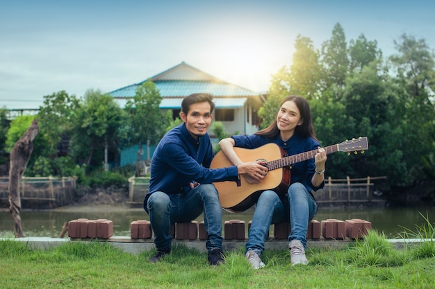 Familie paar gitaar spelen in de tuin thuis