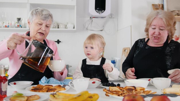 Familie pannenkoeken eten en thee drinken De thee in de kopjes gieten