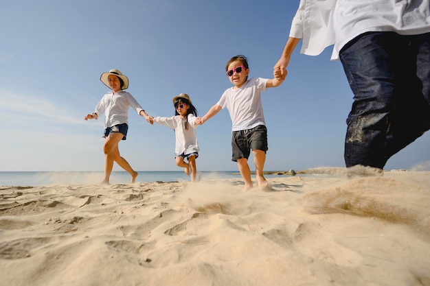 Familie, reizen, strand, ontspannen, levensstijl, vakantieconcept. Familie die genieten van een picknick. Ouders houden hun kinderen handen vast en wandelen op het strand bij zonsondergang in vakantie.