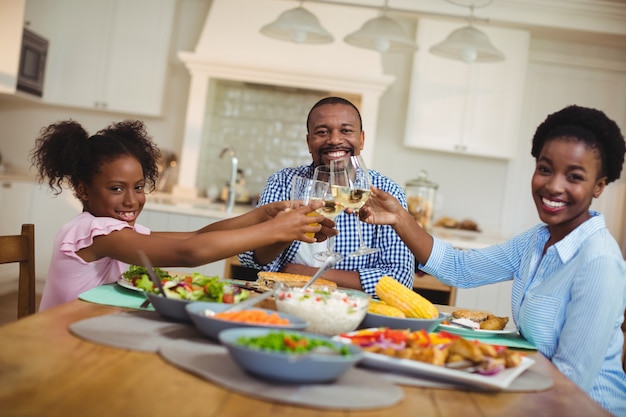 Familie roosteren glazen wijn en sap op eettafel