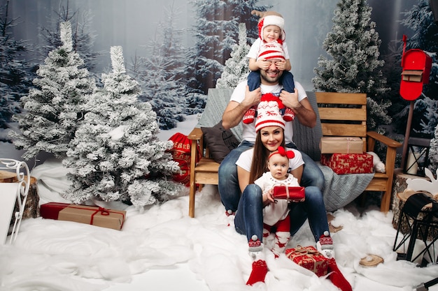 Familie samen met Kerstmis in kunstmatig bos onder sneeuwval