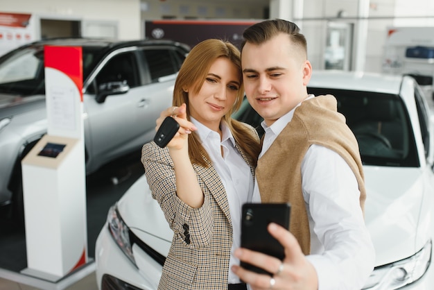 Familie selfie in dealer. Gelukkig jong koppel kiest en koopt een nieuwe auto voor het gezin.