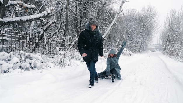 Familie sleeën in de winter winter activiteit gelukkig lachen speels getrouwd echtpaar geniet