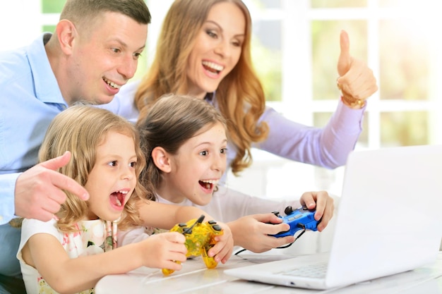 Familie spelen op laptop aan tafel