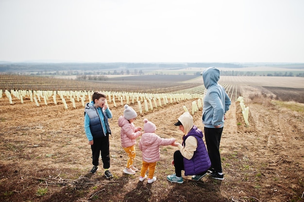 Familie staat in het vroege voorjaar tegen wijngaard