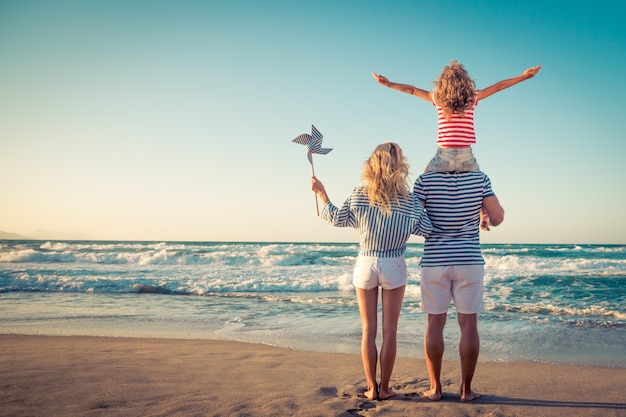 familie staat op het strand en kijkt naar de blauwe zee