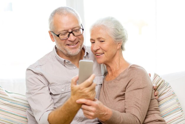 familie, technologie, leeftijd en mensen concept - gelukkig senior koppel met smartphone die thuis selfie maakt