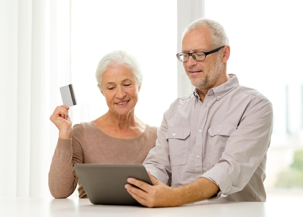 familie, technologie, leeftijd en mensenconcept - gelukkig hoger paar met de computer van tabletpc en creditcard thuis