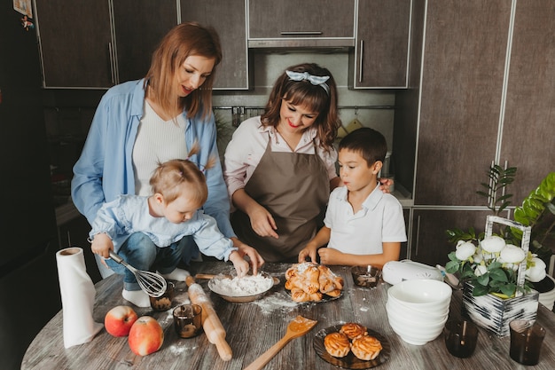 Familie: twee vrouwen en kinderen bereiden een verjaardagstaart in de keuken.