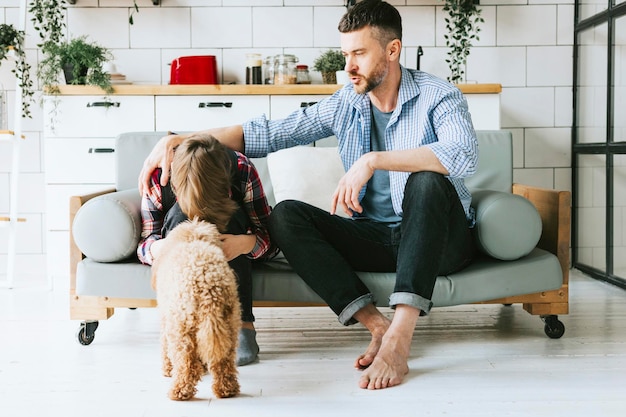 familie vader jonge man kalmeert zijn zoon schattige tienerjongen op de bank in een gezellig appartement quality time met je familie overstuur tiener verliest in voetbal