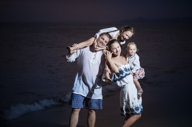 Familie vader moeder kind meisje en baby op het strand tegen de zee en de prachtige zonsondergang