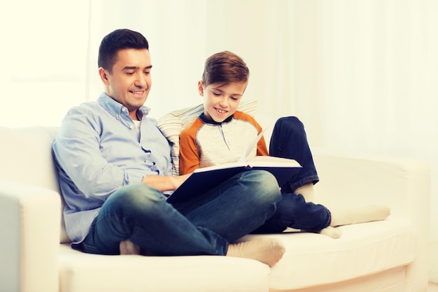 familie, vaderschap, generatie, literatuur en mensen concept - gelukkige vader en zoon leesboek thuis