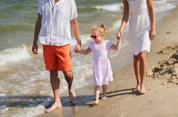 familie, vakantie, adoptie en mensen concept - gelukkige man, vrouw en klein meisje in zonnebril wandelen op het zomerstrand