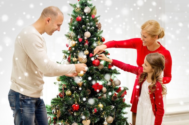 familie, vakantie, generatie en mensen concept - lachende familie kerstboom thuis versieren