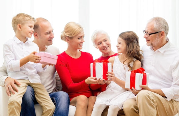 familie, vakantie, generatie, kerst en mensen concept - lachende familie met geschenkdozen die thuis op de bank zitten